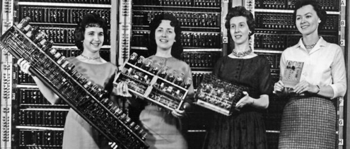 Image de quatre femmes devant un très vieil ordinateur